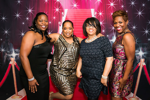 Guests posing on a red carpet in front of a step and repeat backdrop in Las Vegas