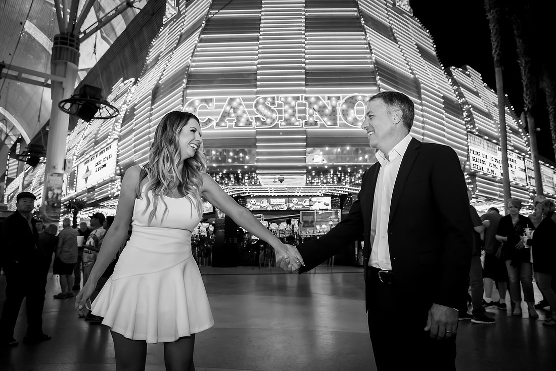 Couple holding hands during a Las Vegas anniversary photo session in front of the Fremont Street casino lights.