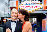 Couple posing beneath the Welcome to Downtown Las Vegas sign during an anniversary photo session.